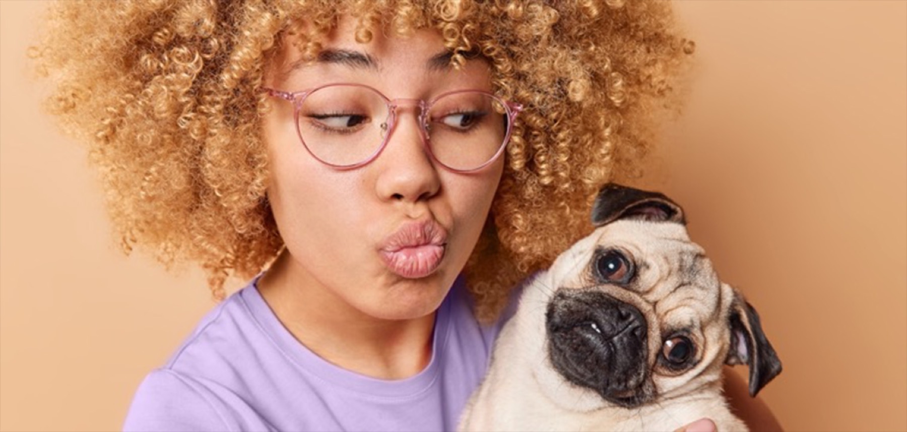 A pet owner puckering up next to her pug